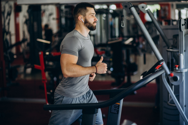 homme musclé avec gros bras sur tapi de course